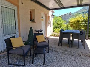 a patio with a table and chairs and a table at Gite des vallées d'Azur in Puget-Théniers