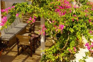 a porch with pink flowers and a table and a bench at Case De Drymona 1 in Kythira