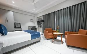 a hotel room with a bed and two chairs at Hotel Sun Lorem, Ahmedabad in Ahmedabad +35 photos
