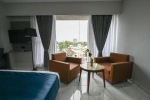 a room with two chairs and a table and a window at Hotel Sun Lorem, Ahmedabad in Ahmedabad