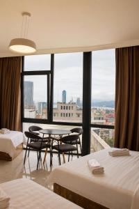 a hotel room with two beds and a table and chairs at VELOR Hotel apartment in Batumi