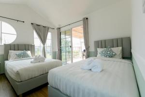 two beds with towels on them in a bedroom at ศรีคำน่านรีสอร์ท in Ban Muang Chang Tai