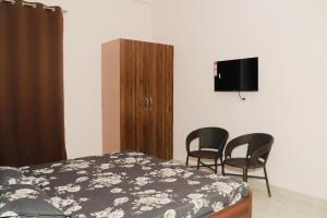 a bedroom with a bed and two chairs and a tv at Nirvana Homestay in Chamba