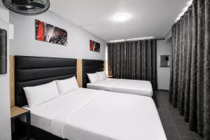 a hotel room with two beds and a window at Hotel Metro Lodge Beach in Durban