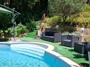 a swimming pool in a yard with chairs and grass at Gite des vallées d'Azur in Puget-Théniers