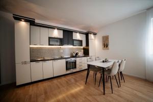 a kitchen with white cabinets and a table and chairs at Estilo Apartments in Prishtinë