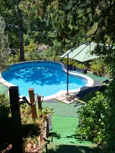 a large blue swimming pool with an umbrella at Gite des vallées d'Azur in Puget-Théniers