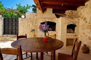 a wooden table with a vase of flowers on a patio at Villa Argiro Plaka Crete in Plaka