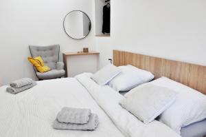 a bedroom with a white bed with a chair and a mirror at Centrum Comfort Apartment in Rimavská Sobota