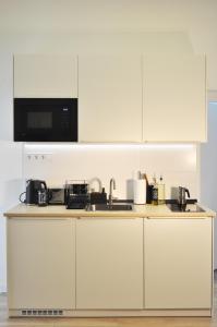a white kitchen with a sink and a microwave at Centrum Comfort Apartment in Rimavská Sobota