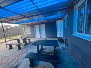 a patio with two picnic tables and a blue ceiling at HavenTrust Guest house in Goodwood