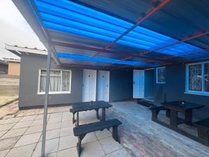 two picnic tables under a blue canopy on a patio at HavenTrust Guest house in Goodwood