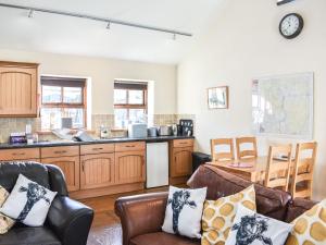 a living room with leather chairs and a kitchen at Riverbank Cottage-Uk42229 in Low Borrowbridge