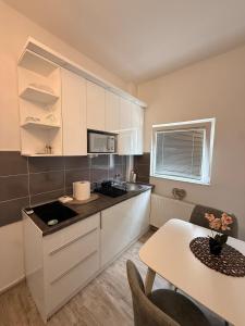 a kitchen with white cabinets and a table at Modern Cozy Apartment Lola in Doboj