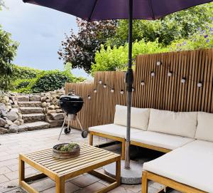 a patio with a table and an umbrella and a grill at Boutique Home Bad Iburg in Bad Iburg