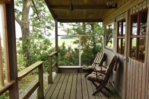 a porch with two rocking chairs and a window at Countryside Eco Natuurhuisjes in Ee