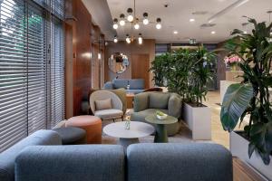 a lobby with blue couches and tables and plants at Hotel Oliwski in Gdańsk