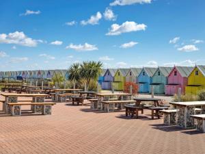 a group of tables and benches in front of colorful buildings at Staying Inn in West Mersea