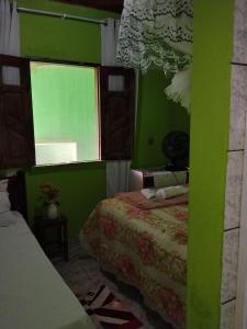a green bedroom with two beds and a window at Quarto Oliveira in Ibicoara +2 photos