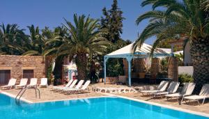 a pool with chairs and palm trees and a tent at Patmos Garden in Skala
