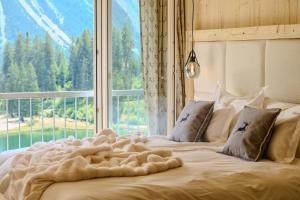 a bed in a room with a large window at appartamaint tscherv by Arosa Vacations, Exklusive Wohnung im Zentrum mit Blick auf den Untersee und die Berge inkl Parkplatz in Arosa
