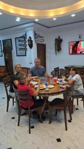 a group of people sitting around a wooden table at Munril Guest in Jaffna