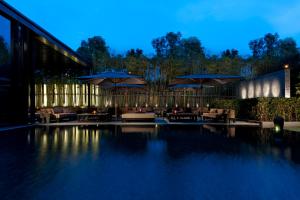 a swimming pool with tables and umbrellas at night at The Puli Hotel And Spa in Shanghai
