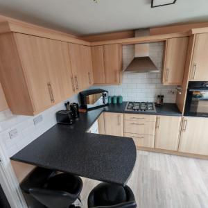 a kitchen with wooden cabinets and a black counter top at Modern 2 bedroom house, sleeps 5 guests, Free parking in Hull