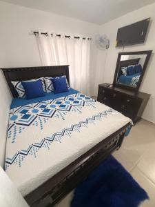 a bedroom with a bed with a blue and white comforter and a mirror at The Palace in San Isidro