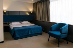 a bedroom with a bed and a blue chair at Житомир by Optima in Zhytomyr +33 photos