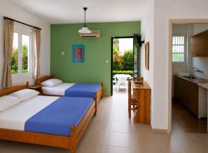 a bedroom with two beds and a kitchen with a table at Araliki Apartments & Studios in Loutra Edipsou