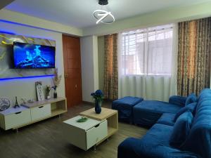 a living room with a blue couch and a tv at DEPPIu in Piura