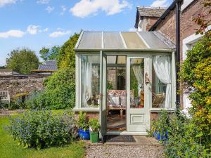 a conservatory with a door in a garden at Ivy Cottage in Crieff