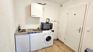 a kitchen with a washing machine and a microwave at Cozy Studio Apartment In The Black Forest in Villingen-Schwenningen