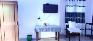 a room with a table and a tv on the wall at White House in Puttalam