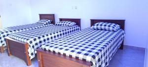 three beds with checkered sheets in a room at White House in Puttalam