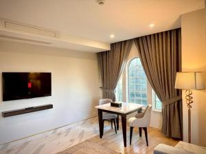 a living room with a table and a tv at Chirani Signature Hotel in Islamabad