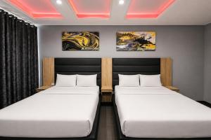 two beds in a room with paintings on the wall at Hotel Metro Lodge Beach in Durban
