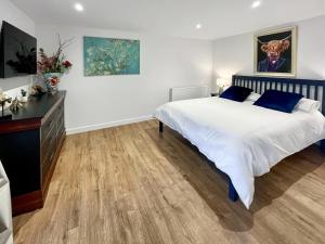 a bedroom with a large bed and a dresser at Wellness Cottage At Tomnauld Farm in Pitlochry