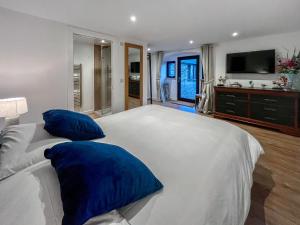 a bedroom with a large white bed with blue pillows at Wellness Cottage At Tomnauld Farm in Pitlochry +20 photos