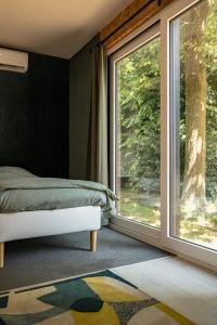 a bedroom with a bed and a large window at Woodboxcabins - Campinggroenpark in Zele