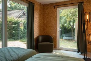 a bedroom with a chair next to a window at Woodboxcabins - Campinggroenpark in Zele