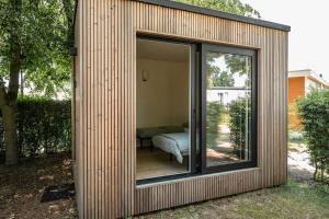 a small wooden house with a sliding glass door at Woodboxcabins - Campinggroenpark in Zele +14 photos