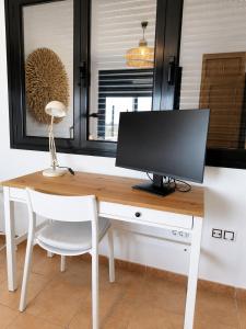 a computer monitor sitting on a desk with a chair at Villa Macaronesia Lajares Fuerteventura Remote work in Majanicho