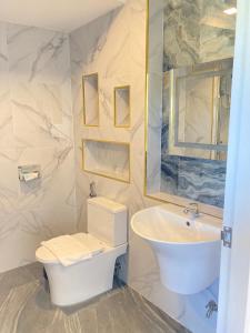 a white bathroom with a sink and a toilet at Monanza Hotel in Ban Thung Prong