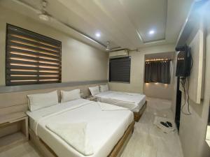 a bedroom with two beds and a television in it at Hotel Bhiwandi Palace Nashik Highway Rd in Bhiwandi
