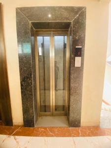 an elevator in a building with a glass door at Hotel Bhiwandi Palace Nashik Highway Rd in Bhiwandi +37 photos