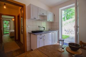 a kitchen with white cabinets and a table and a window at Apartmány Kořenný in Korěnný +31 photos