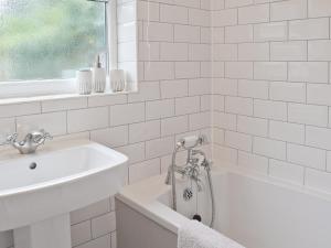 a white bathroom with a tub and a sink at Albion Cottage in Pakefield