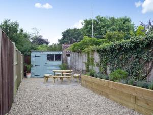 a wooden picnic table in a garden with a fence at Albion Cottage in Pakefield